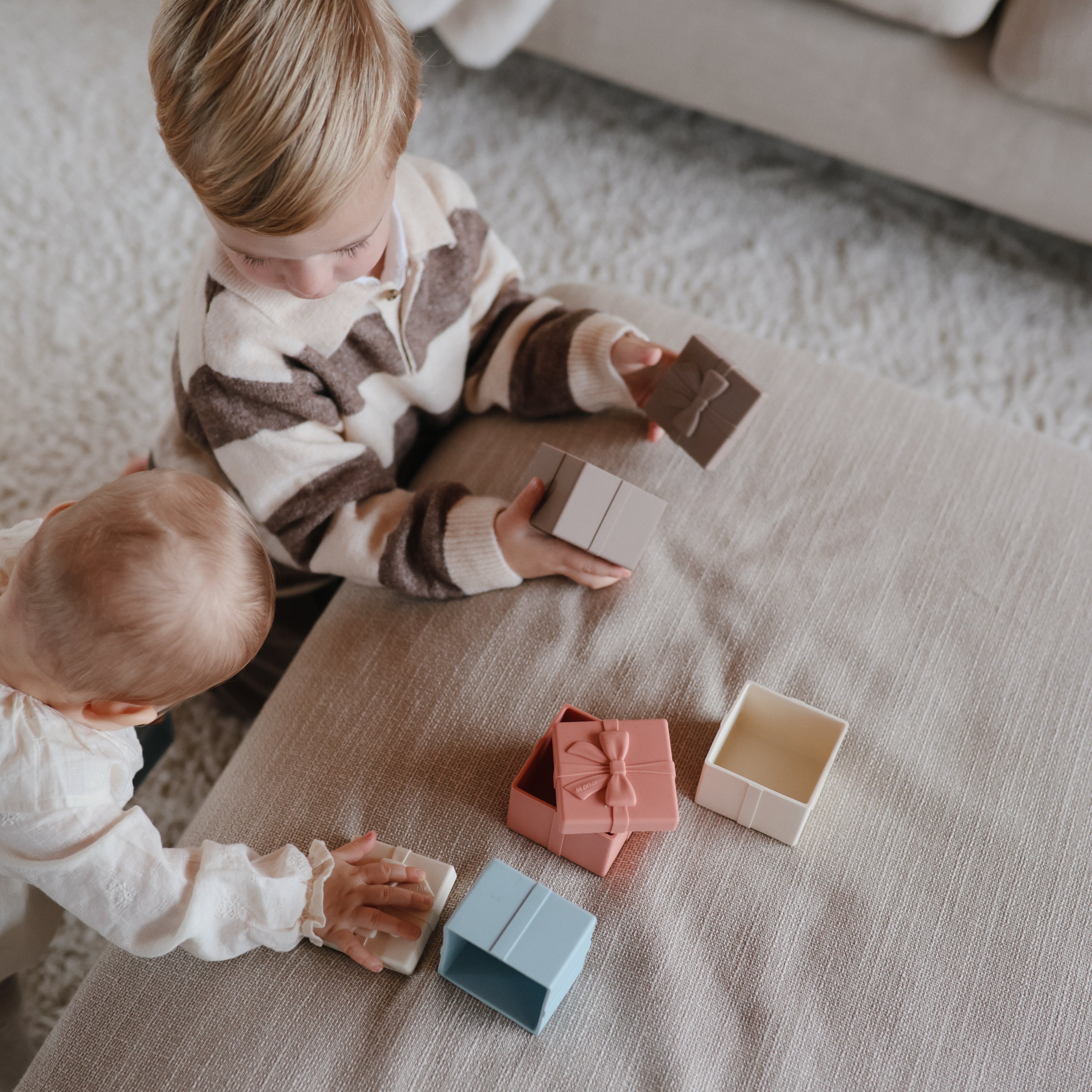 Deux enfants explorant les paquets cadeaux en silicone Mushie