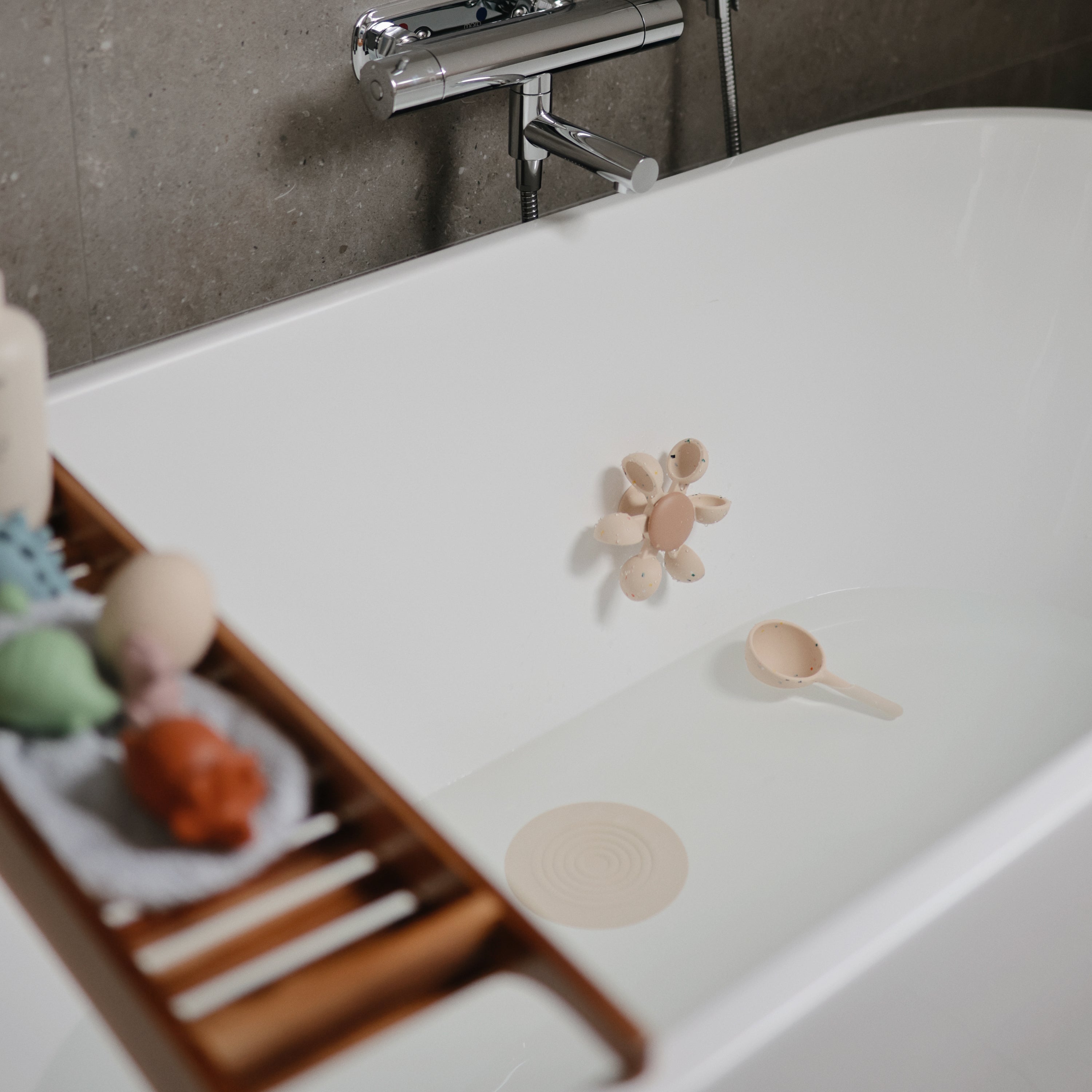 Roue à eau Mushie installée dans une baignoire avec sa cuillère