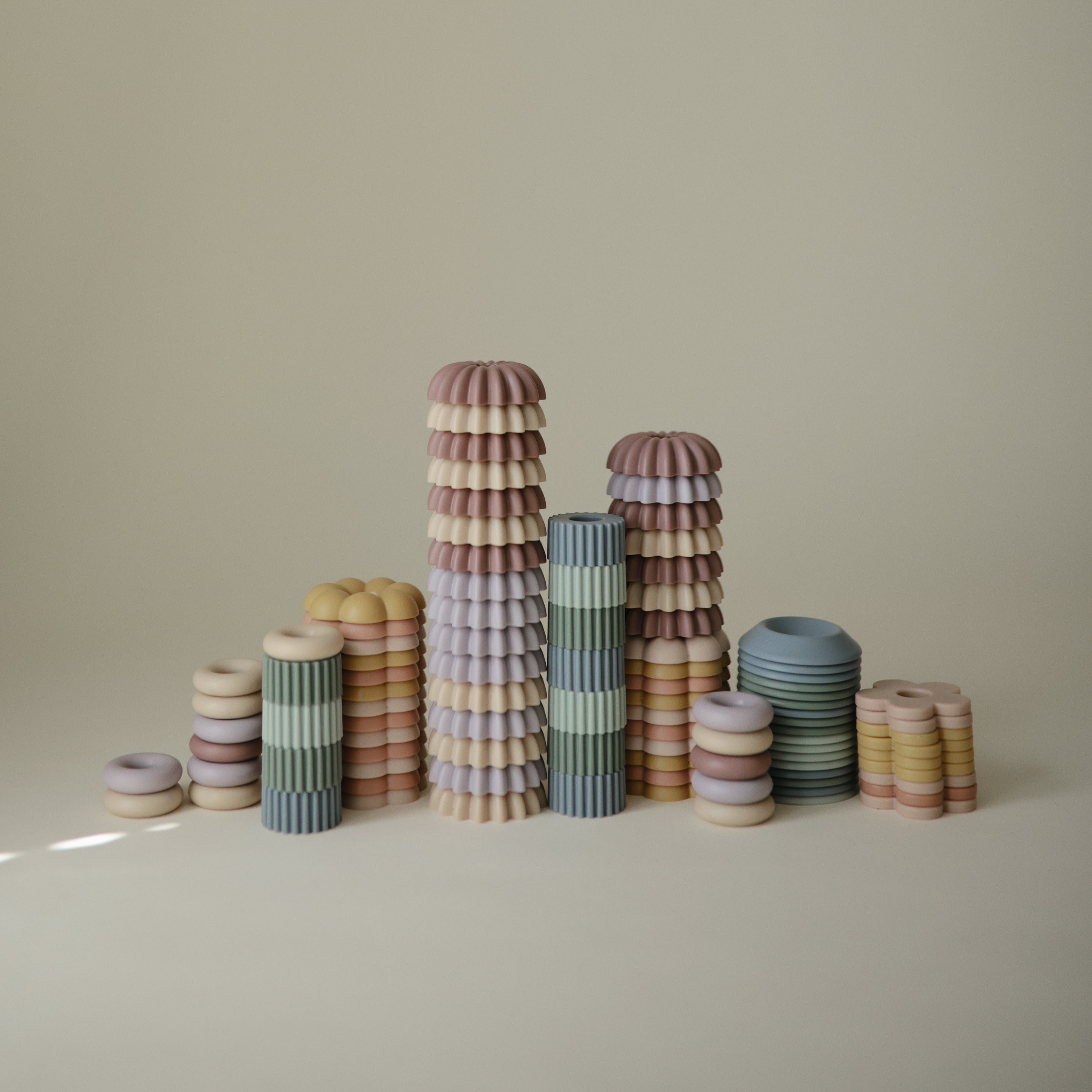 Perles pastel du jeu de laçage Mushie empilées en petites tours