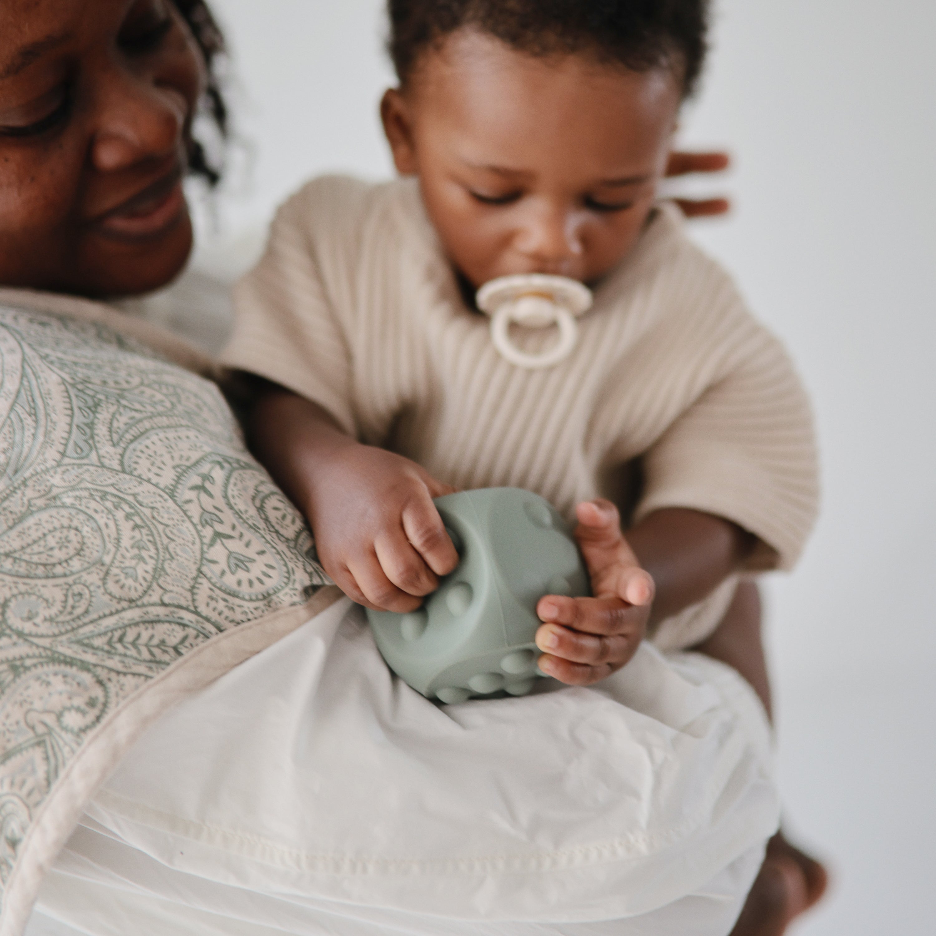 Bébé jouant avec le dé à presser vert Mushie