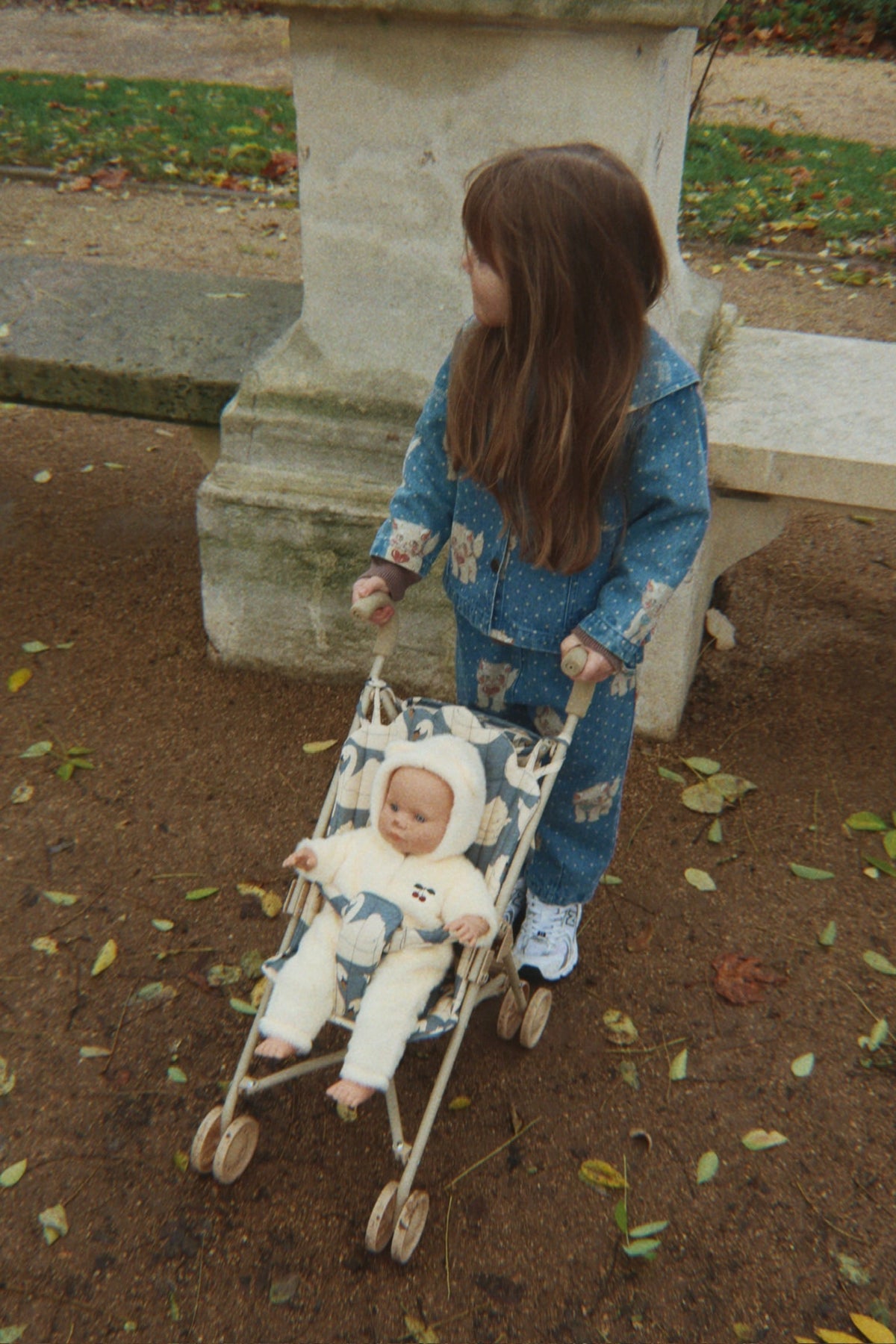 Enfant promenant sa poupée dans la poussette Swan au milieu des accessoires assortis