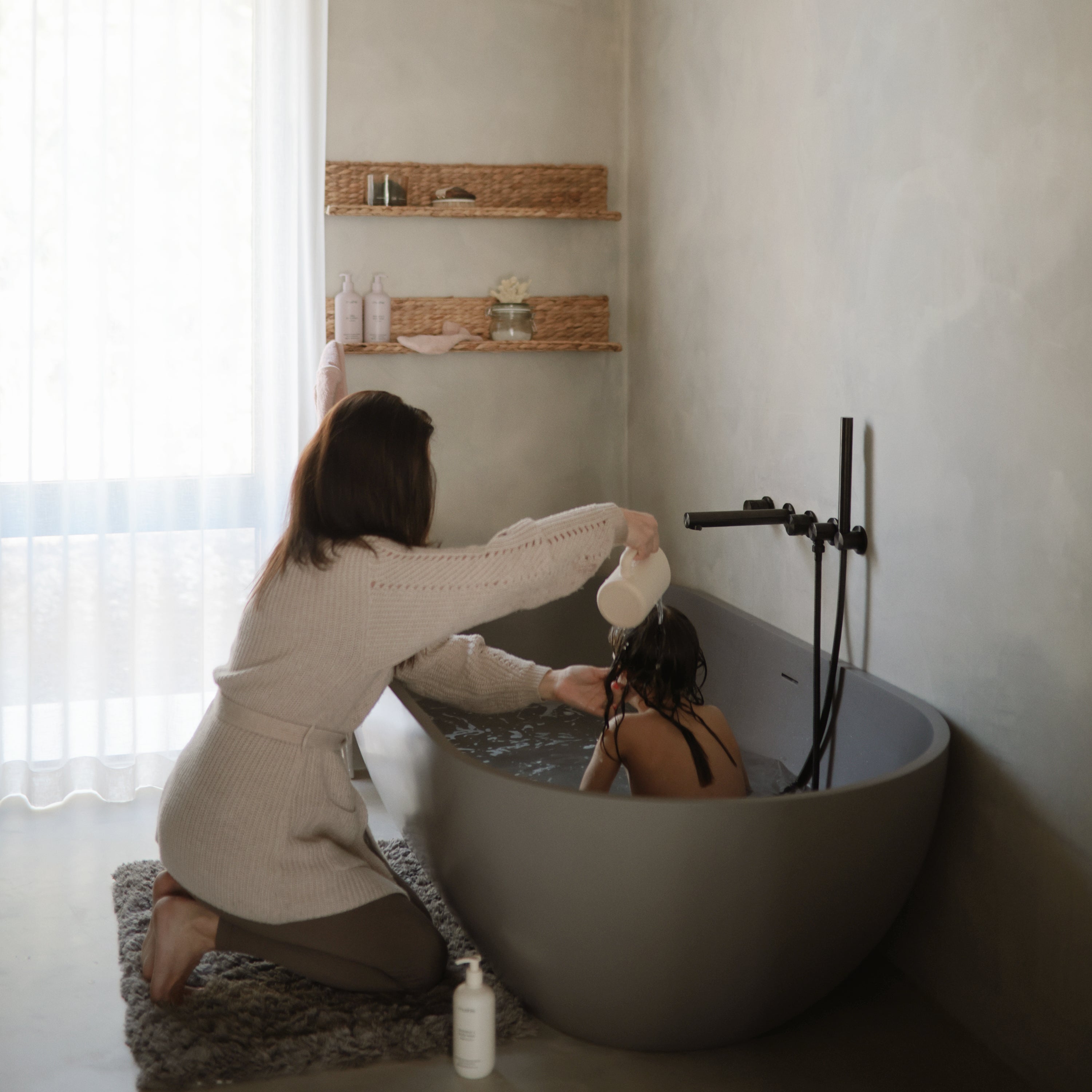 Maman rinçant les cheveux de son enfant avec le gobelet Mushie