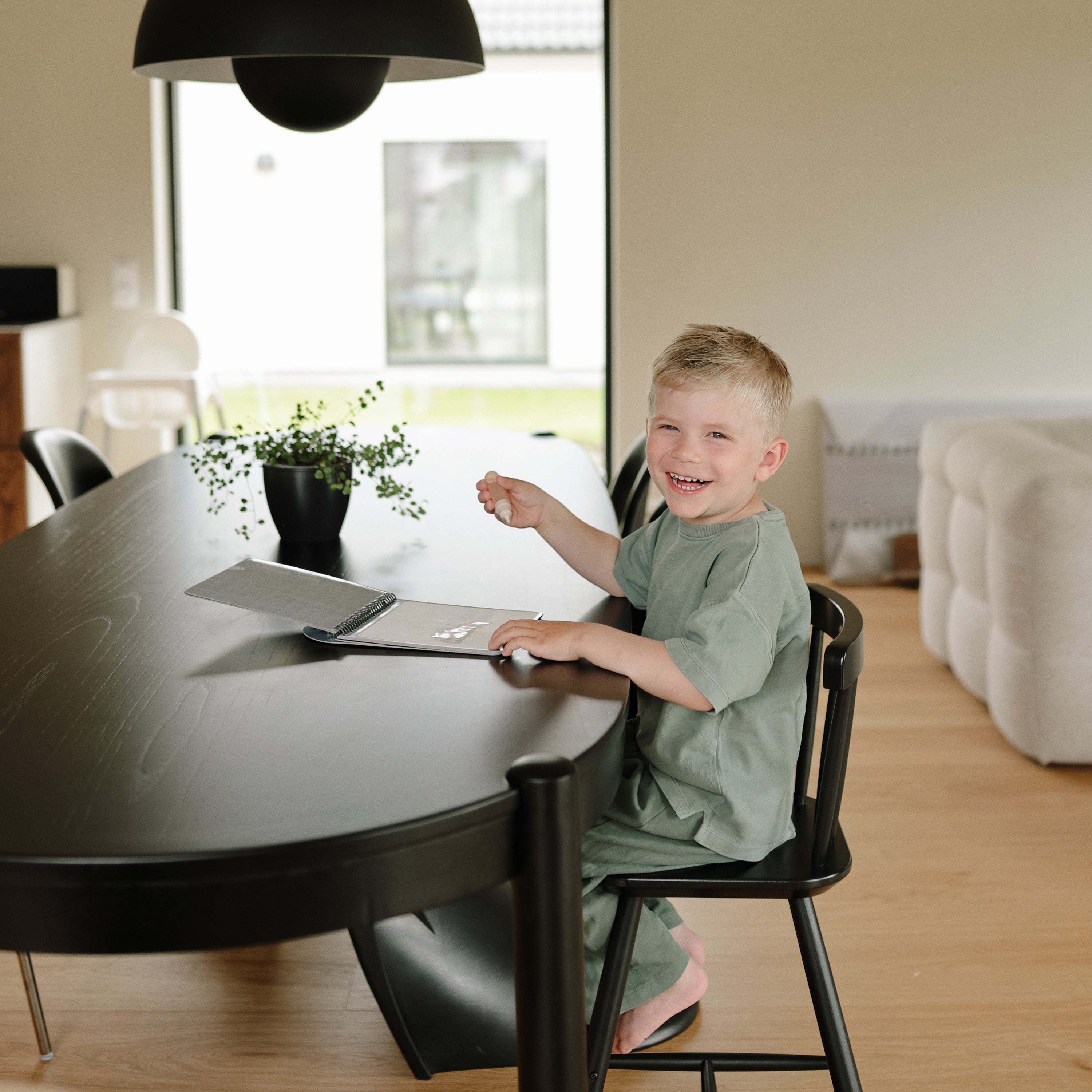 Enfant souriant qui utilise le bloc d'aquarelle réutilisable Mushie