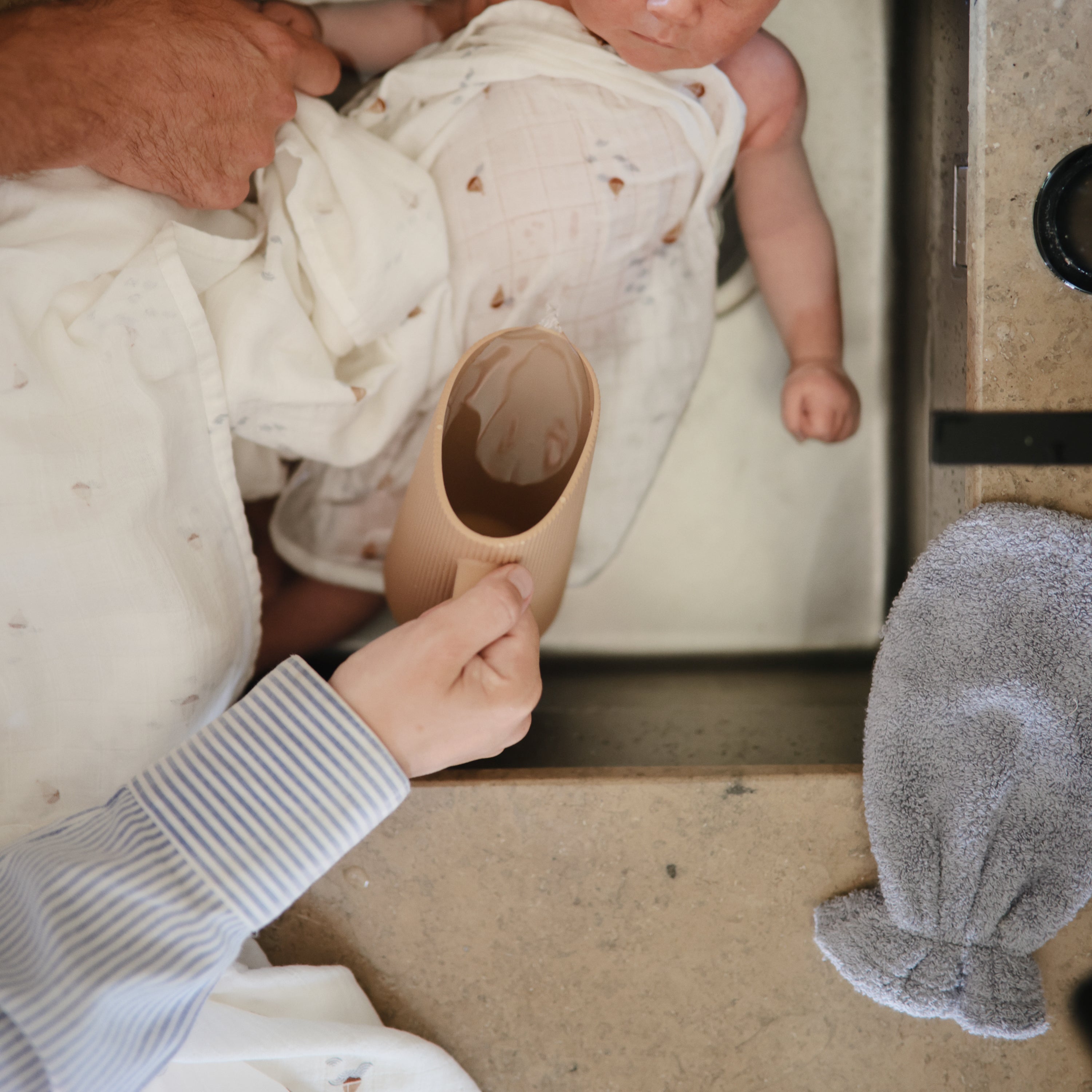 Parents rinçant bébé avec le gobelet Mushie