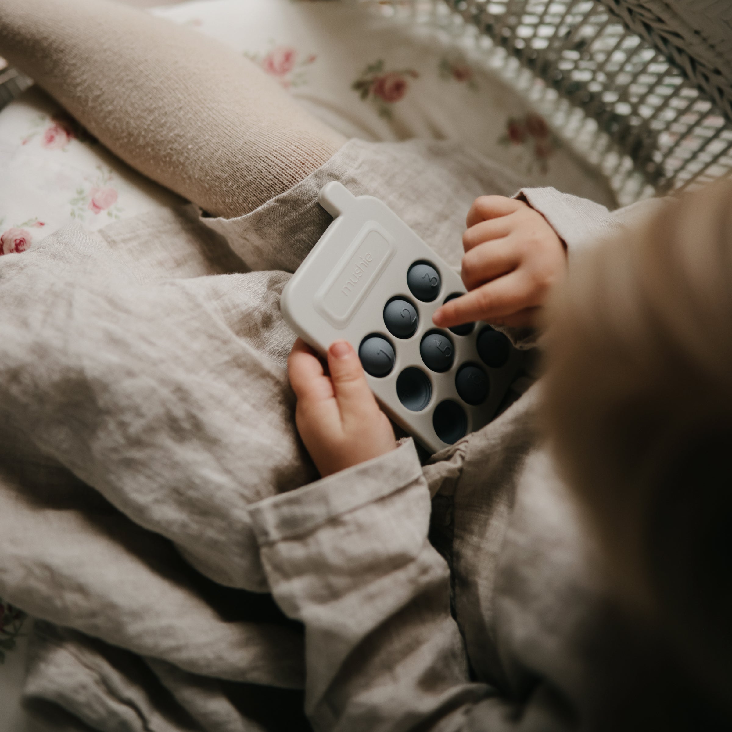 Enfant jouant avec le téléphone à presser Mushie