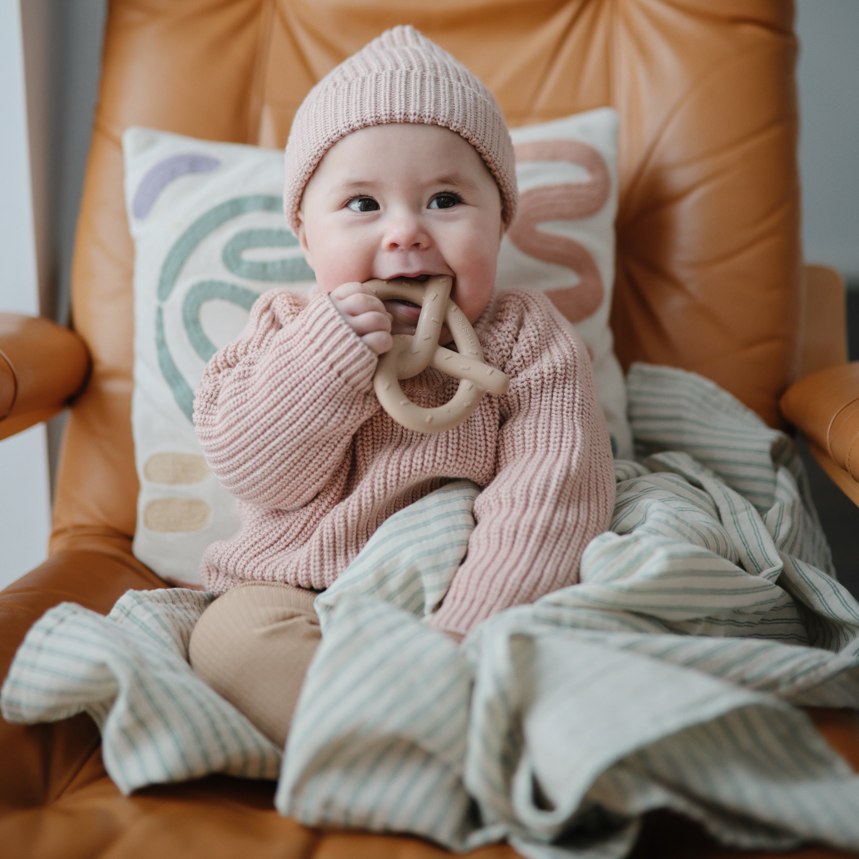 Bébé mordillant l'anneau de dentition Bretzel Mushie