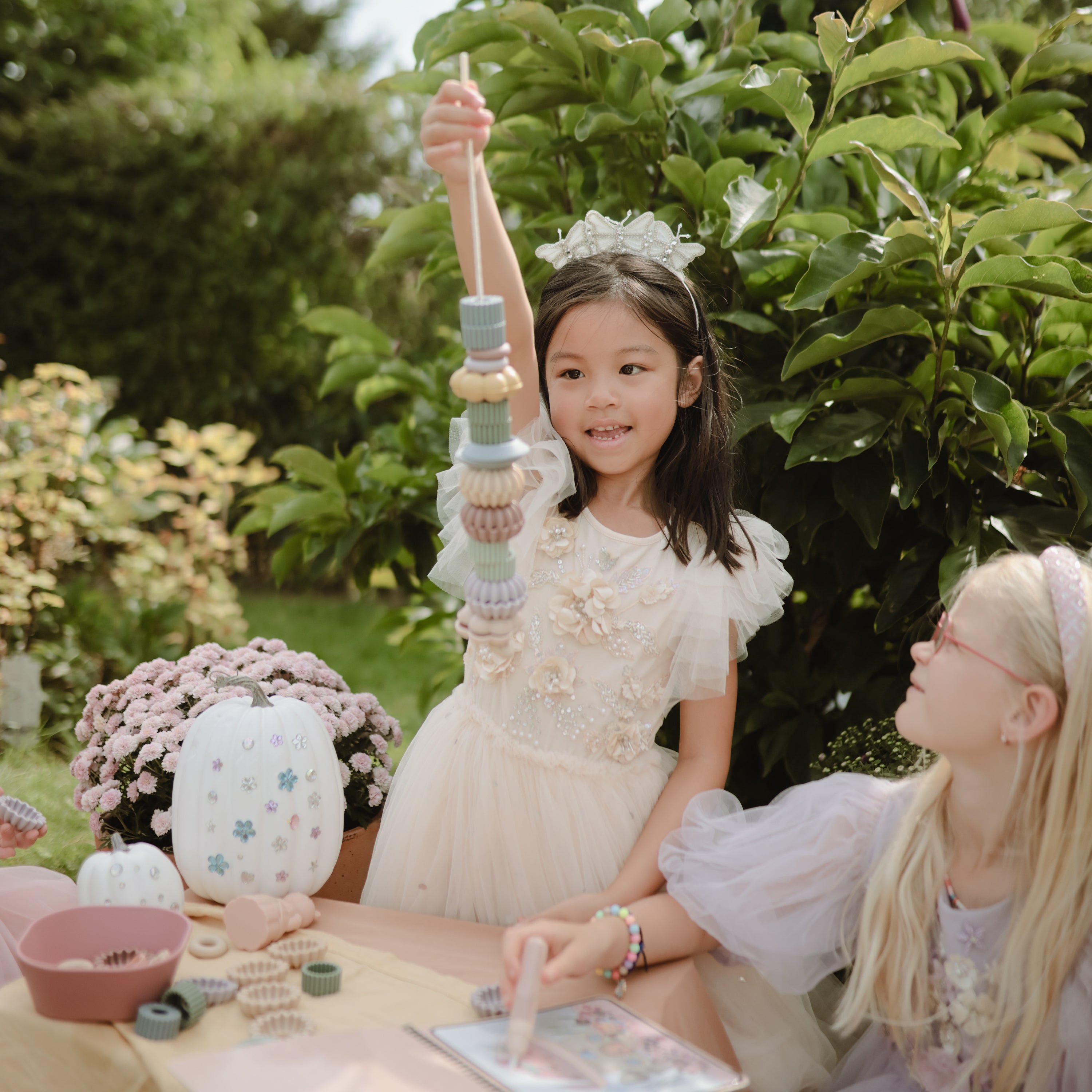 Deux enfants jouant avec le jeu de laçage de perles Mushie au jardin