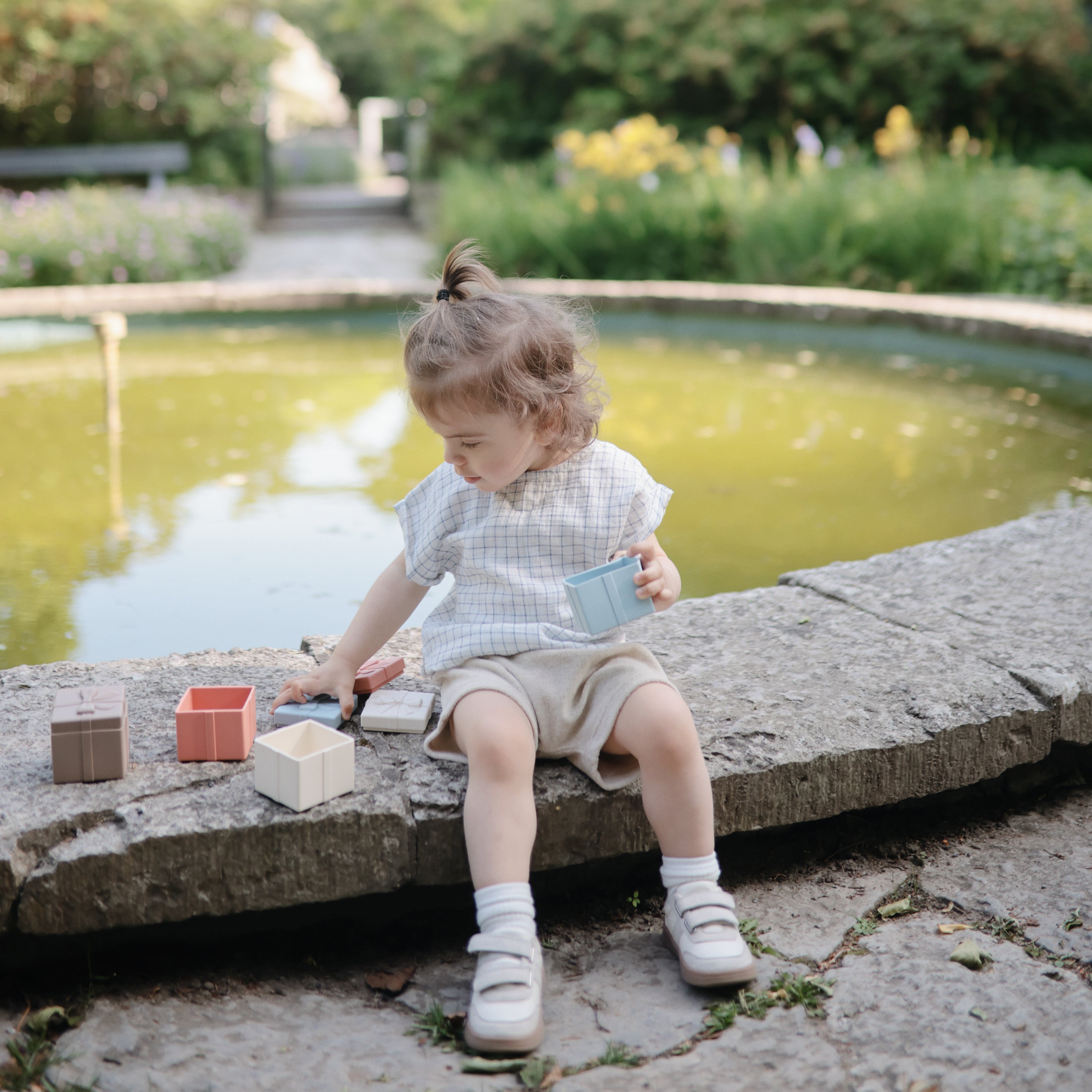 Enfant jouant au bord de l'eau avec le jeu à assortir Mushie Present