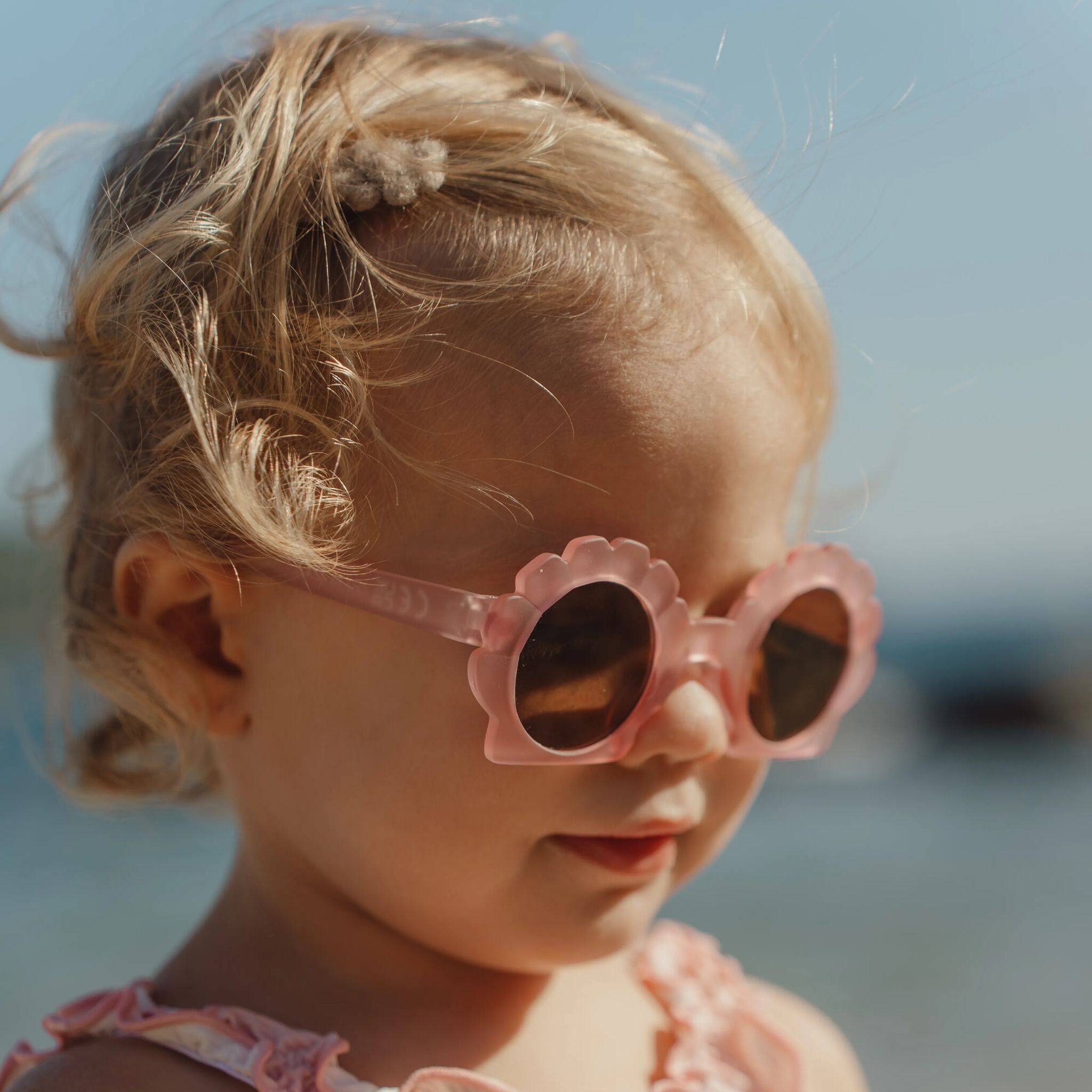 Enfant portant les lunettes de soleil Shell Mermaid Pink à la plage