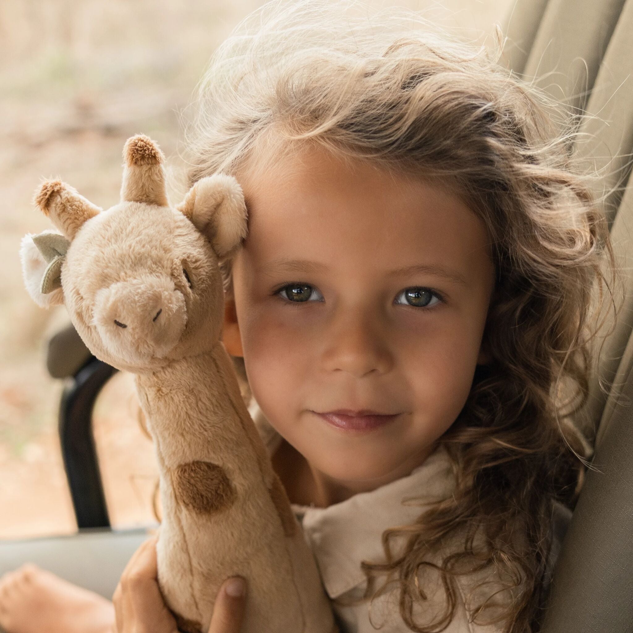 Girafe en peluche jaune Little Dutch tenue par un enfant