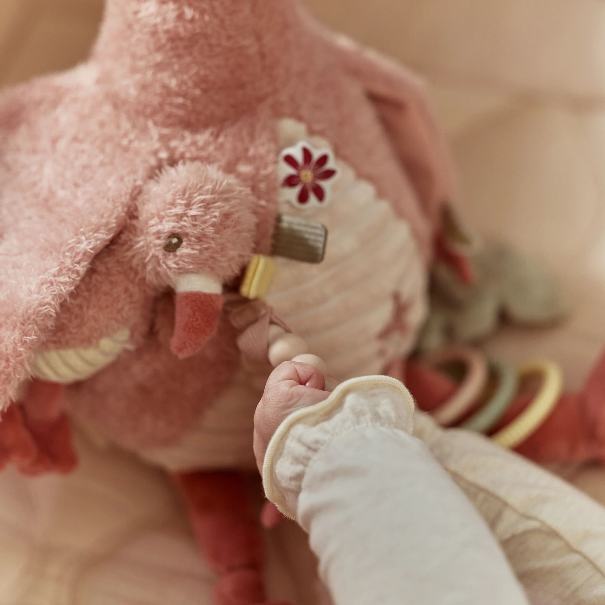 Peluche d'activités Flamant rose posée sur un tapis d'éveil