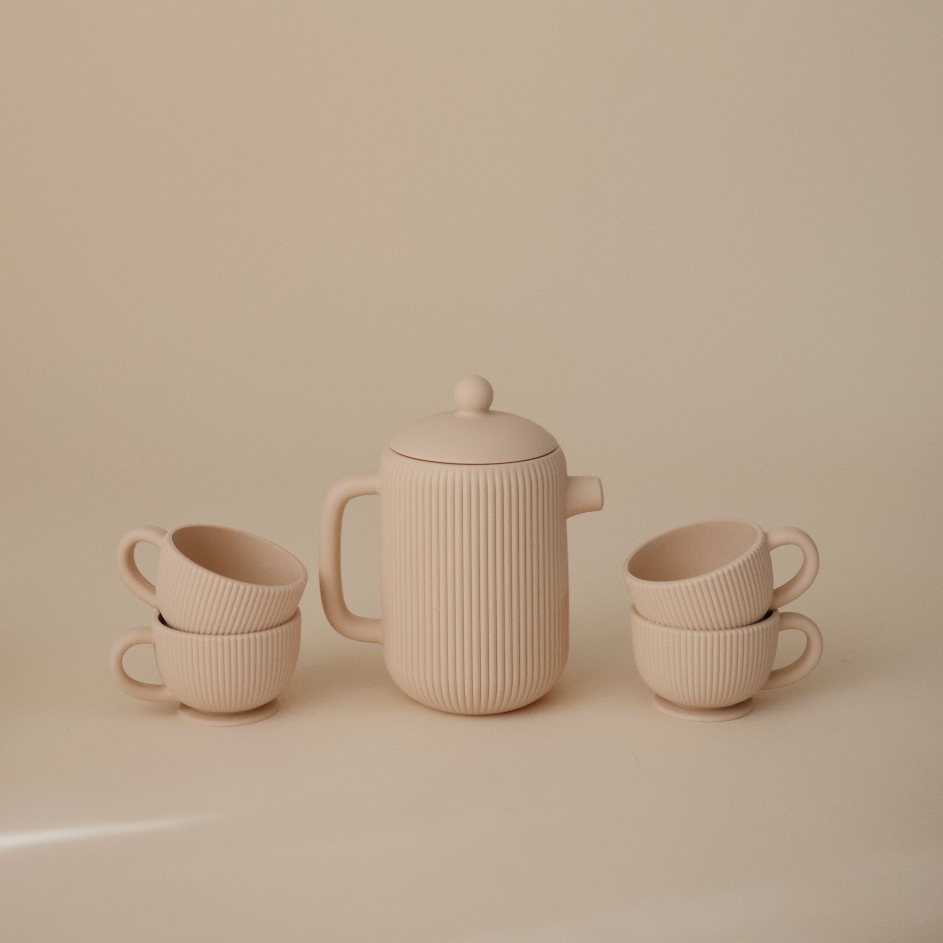 Théière beige Mushie entourée de tasses côtelées