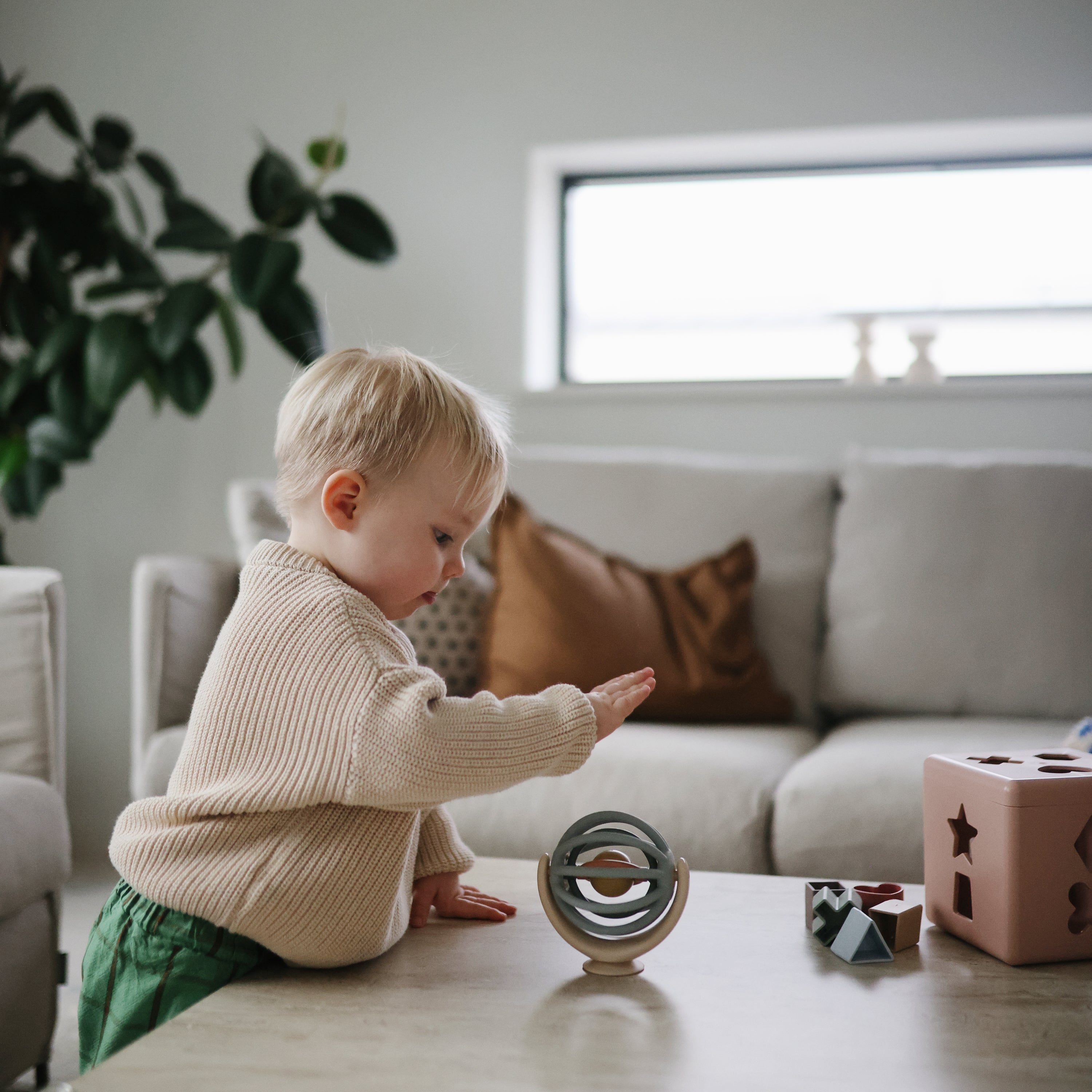 Toupie Balle Mushie au milieu d'autres jouets sensoriels dans un salon