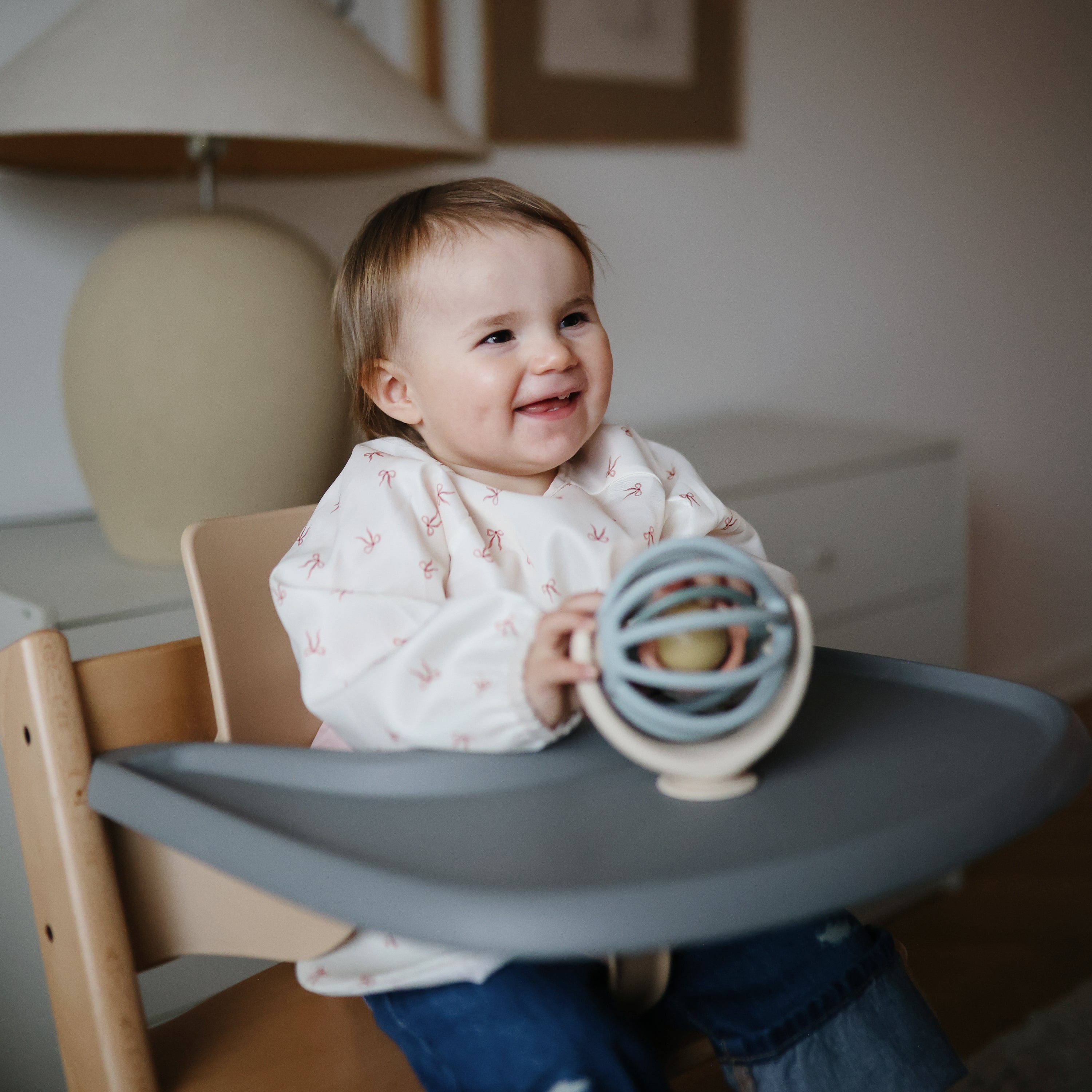 Enfant tenant à pleine main la balle en silicone de la toupie Mushie