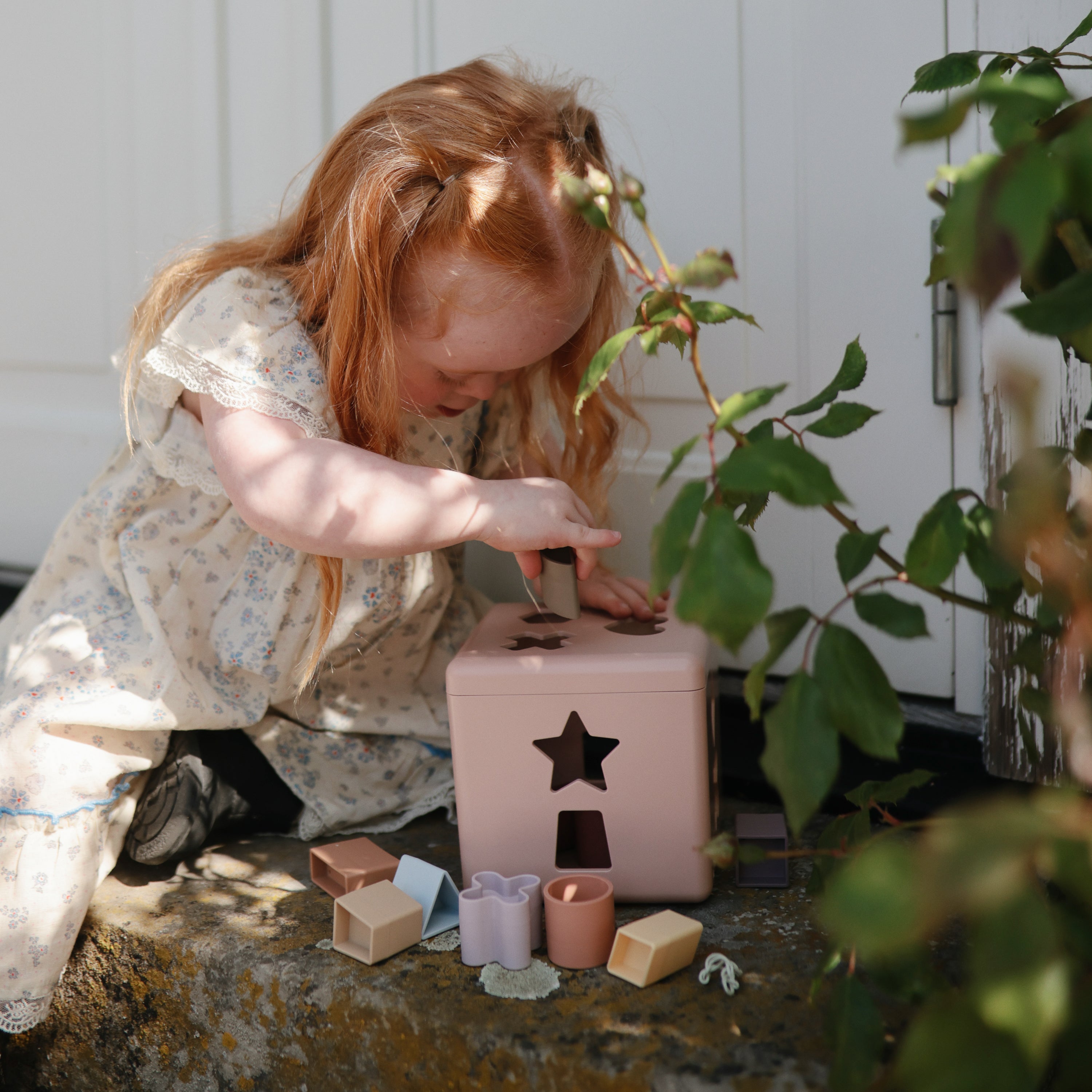 Enfant jouant avec la boîte à formes Mushie