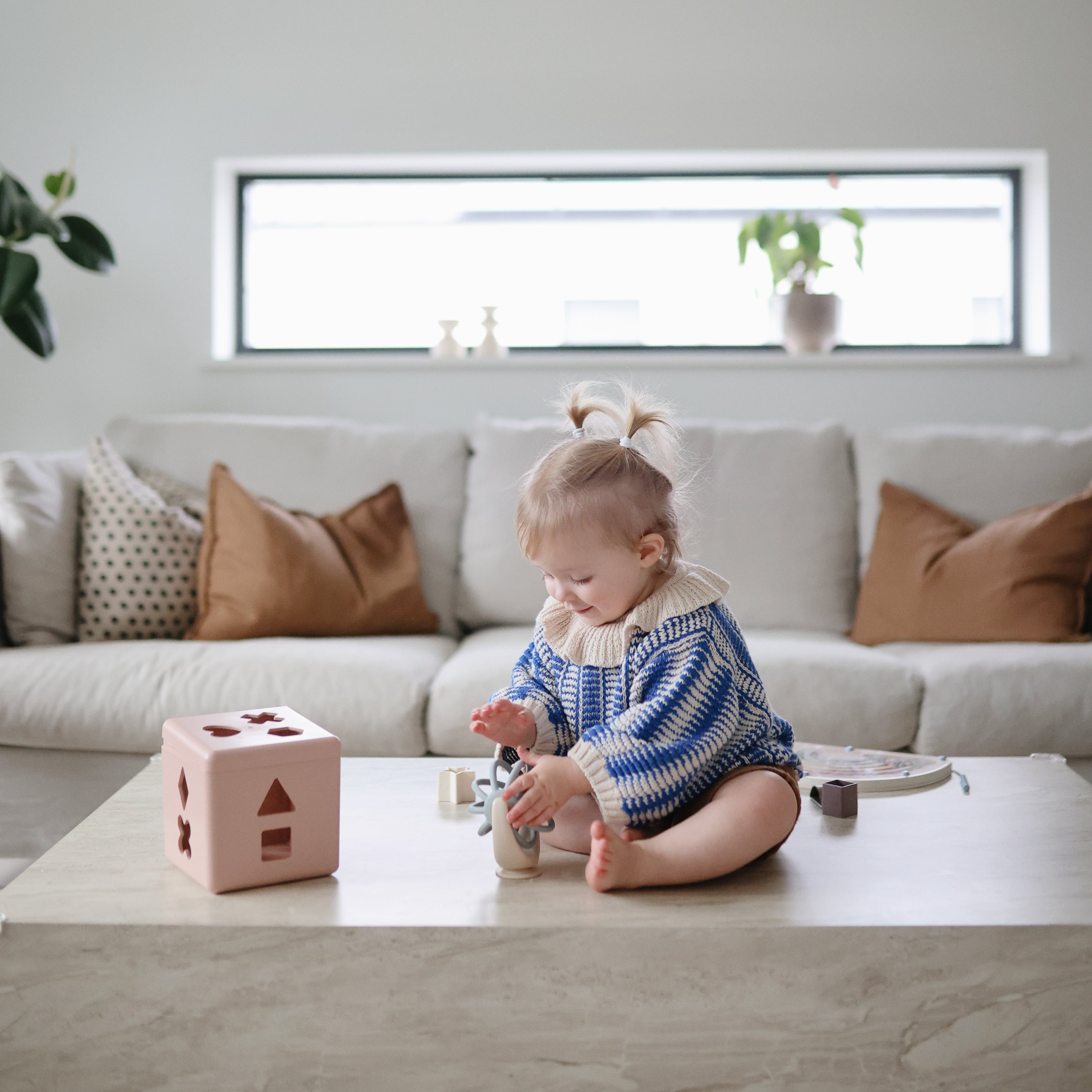 Enfant jouant avec la toupie Balle Mushie et des cubes sur une table basse