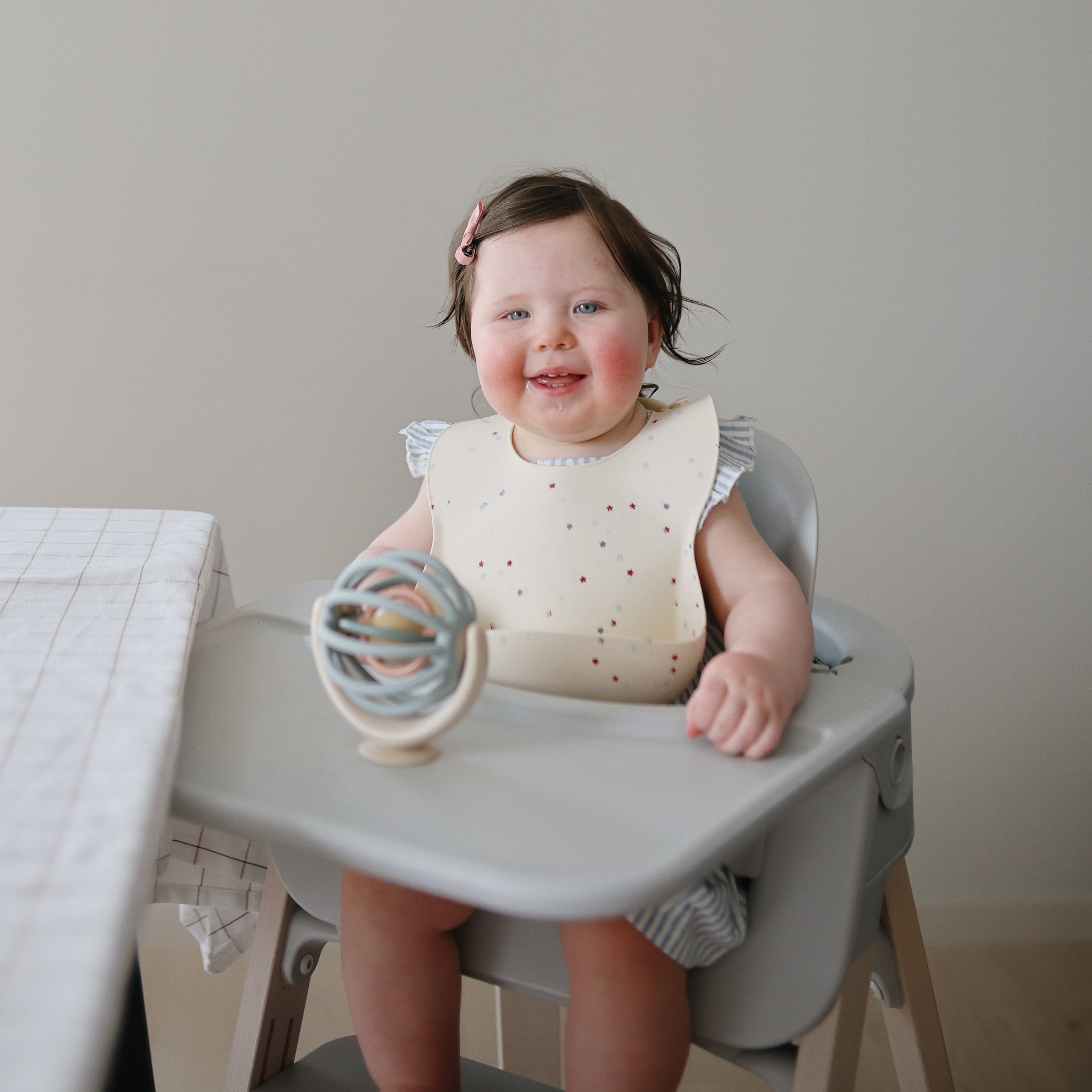 Bébé en chaise haute jouant avec la toupie à ventouse Balle Mushie