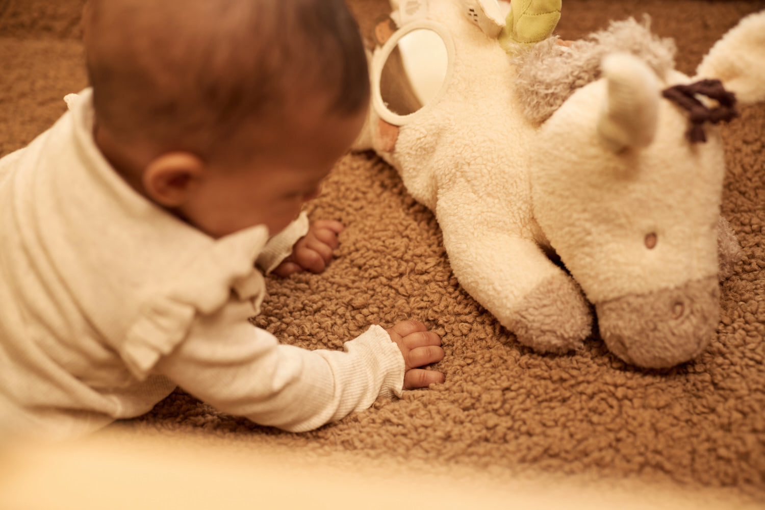 Peluche d'activités Donkey Dinky Jollein dans les bras d'un bébé