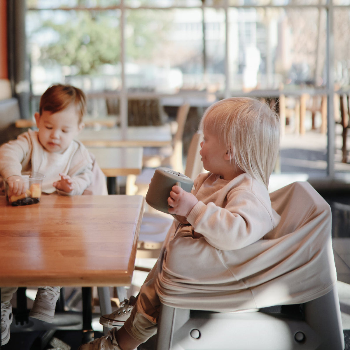 Enfants à table avec un gobelet à goûter Mushie
