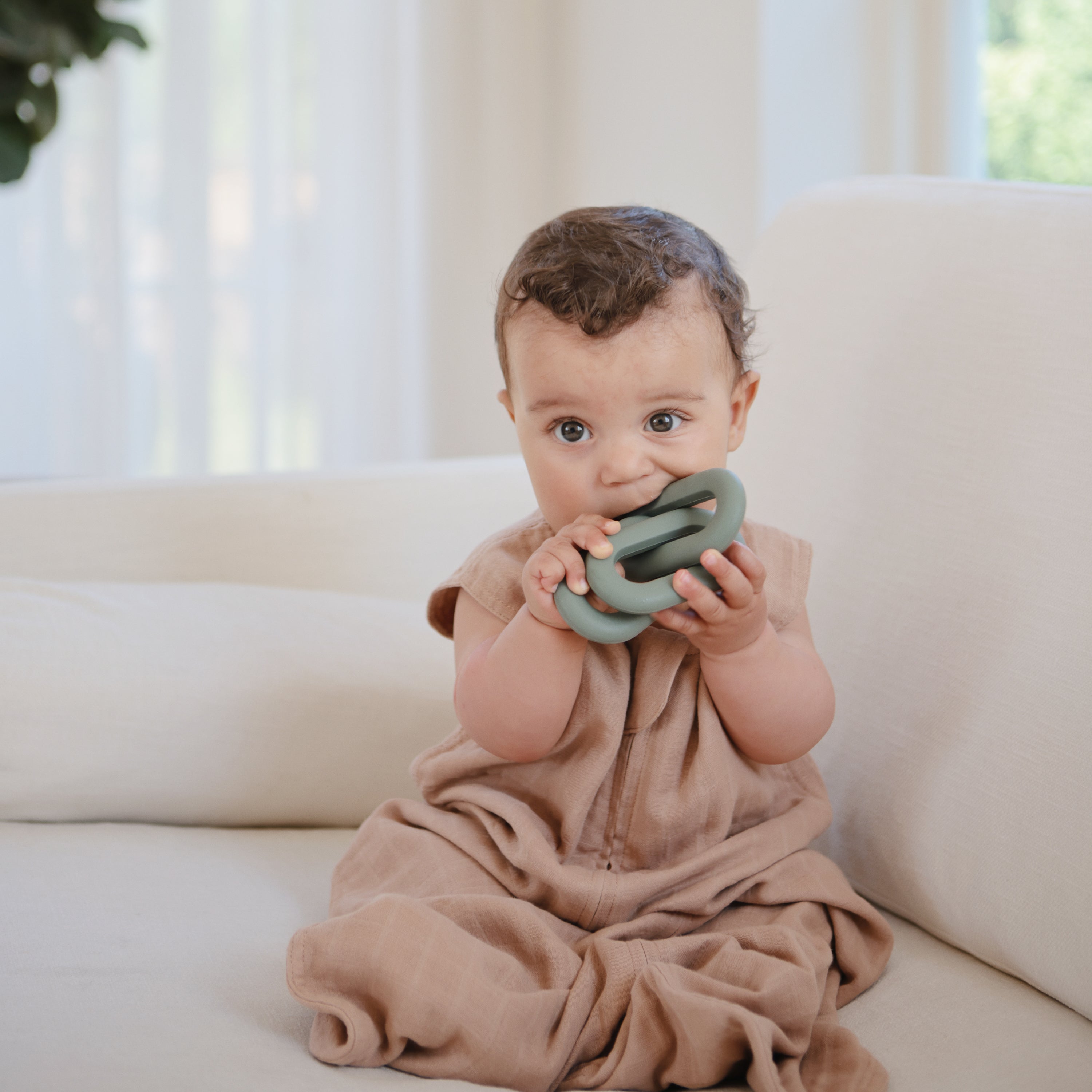 Bébé mordillant l'anneau de dentition Maillons vert Mushie