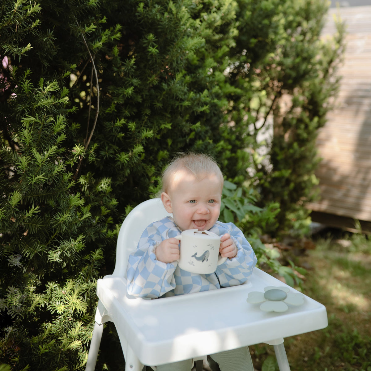 Tout-petit tenant son gobelet à goûter Mushie à deux mains