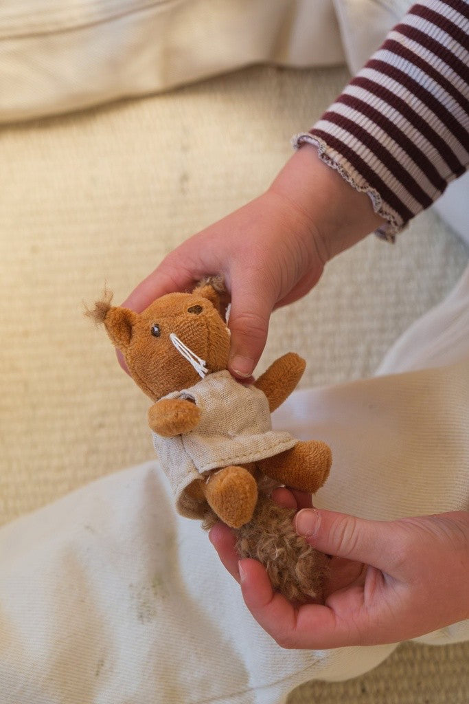 Enfant jouant avec l'écureuil en peluche de la maison de poupées
