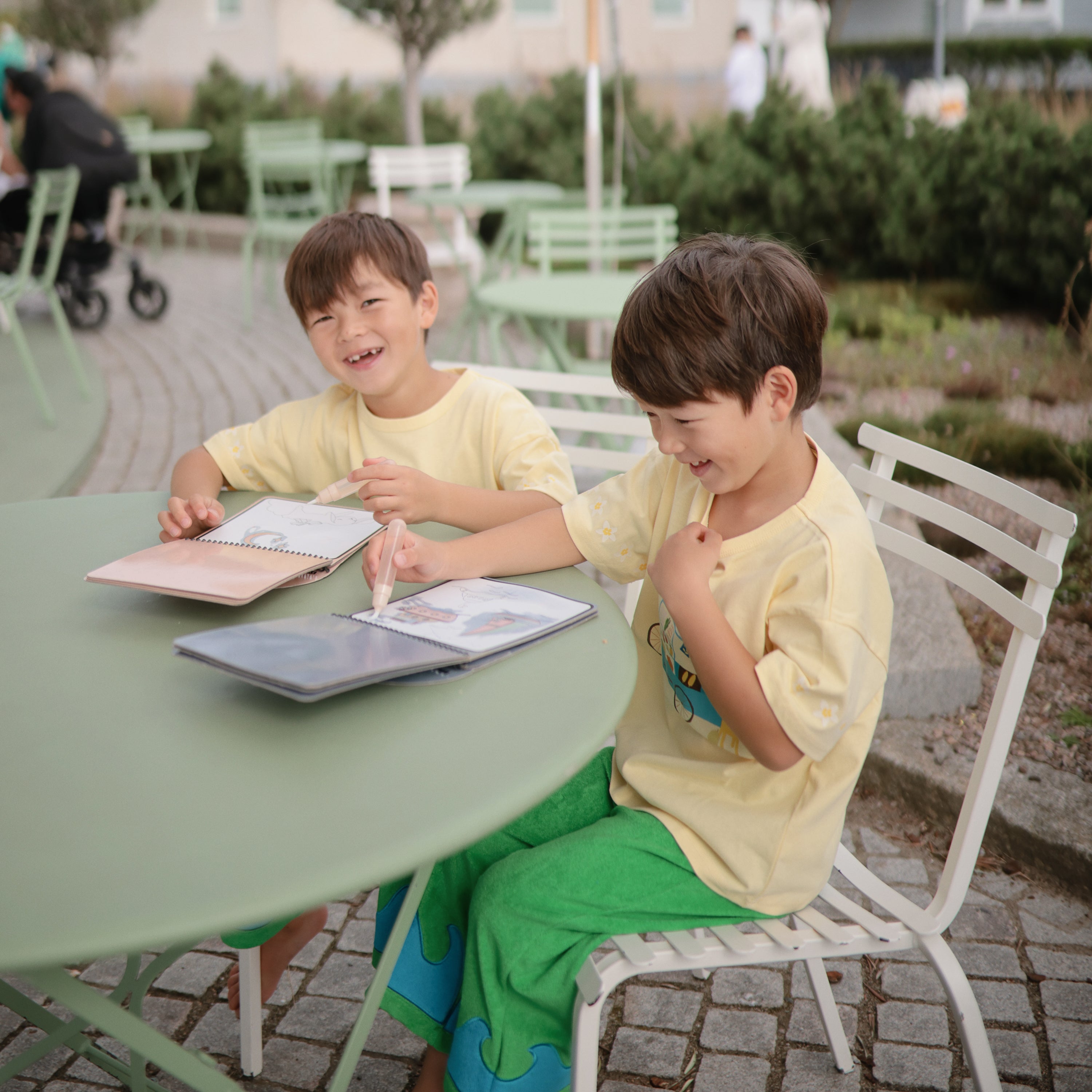 Deux enfants avec leurs blocs d'aquarelle réutilisables Mushie en extérieur
