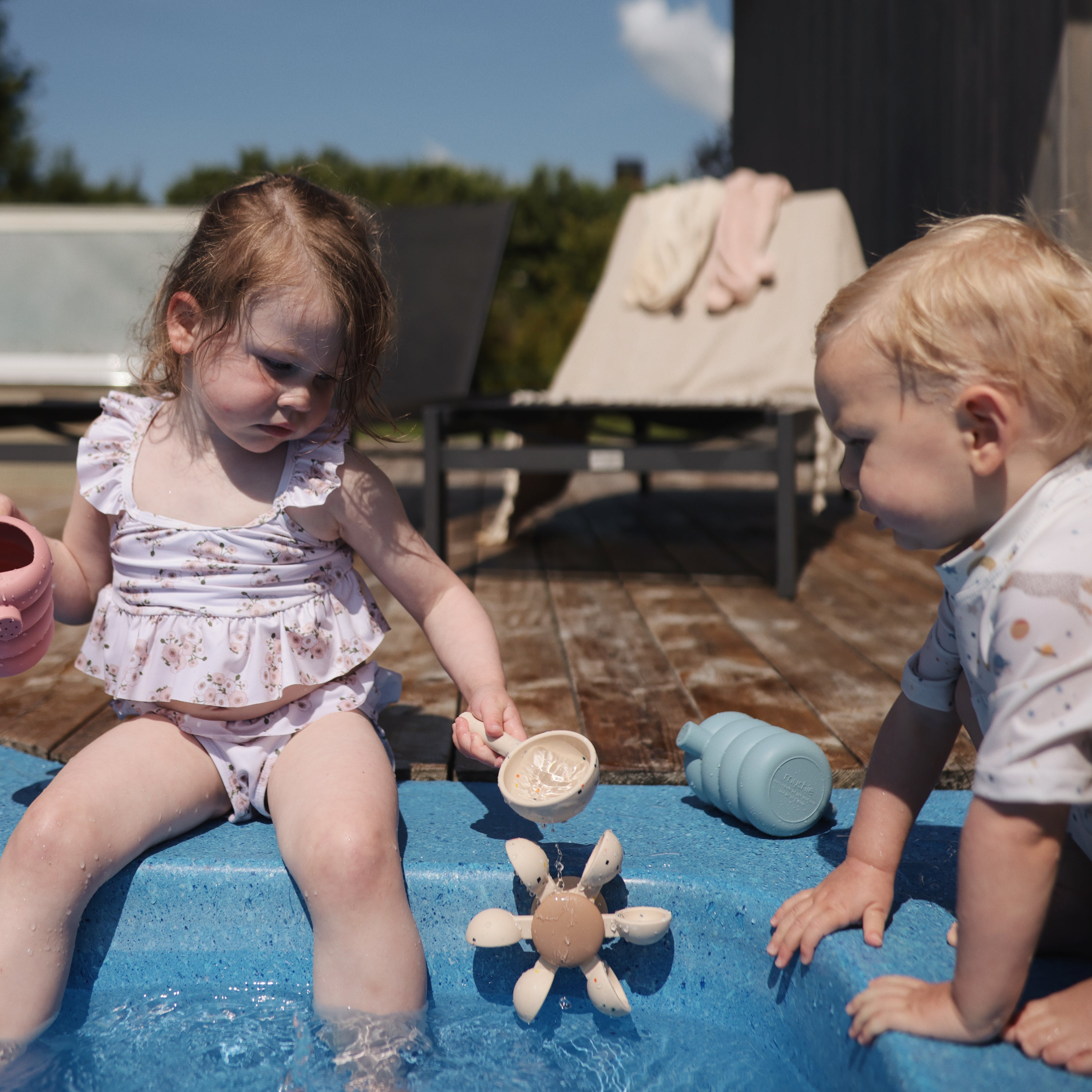 Enfants jouant avec la roue à eau Mushie au bord d'une piscine