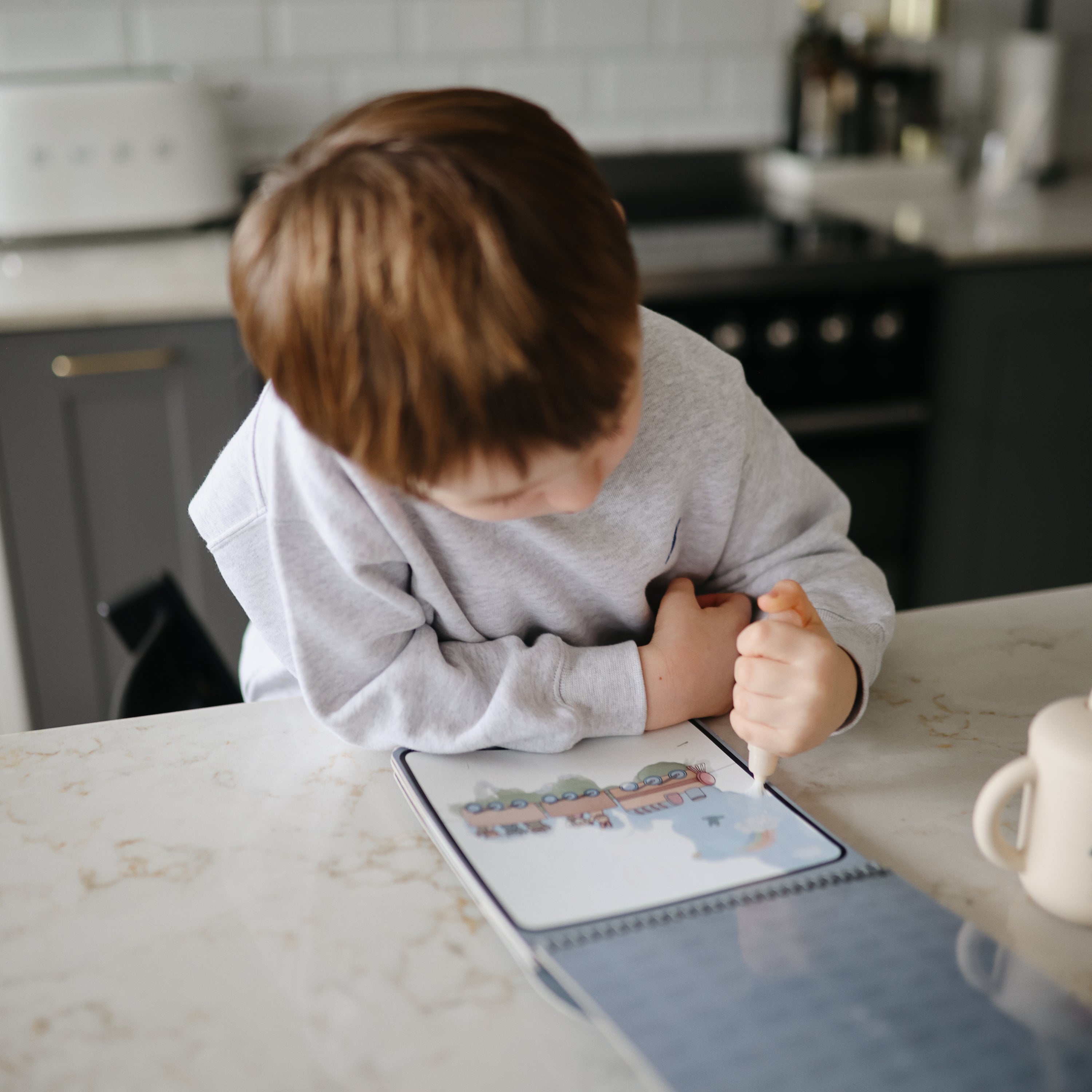 Enfant dessinant dans le bloc d'aquarelle Mushie avec le pinceau à réservoir