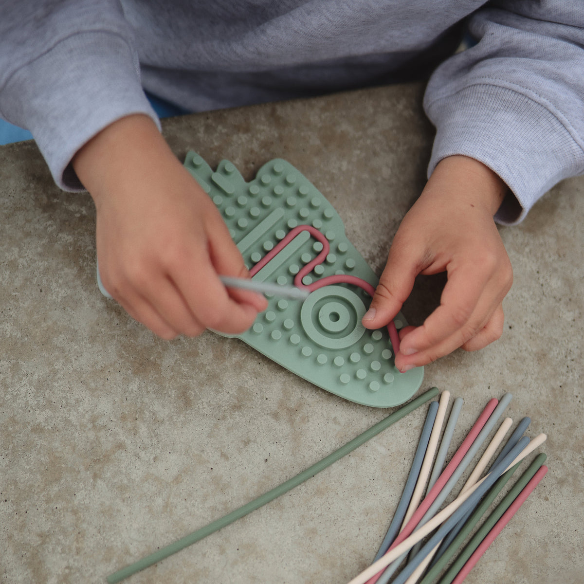 Enfant enfonçant des cordons dans un jouet sensoriel Mushie