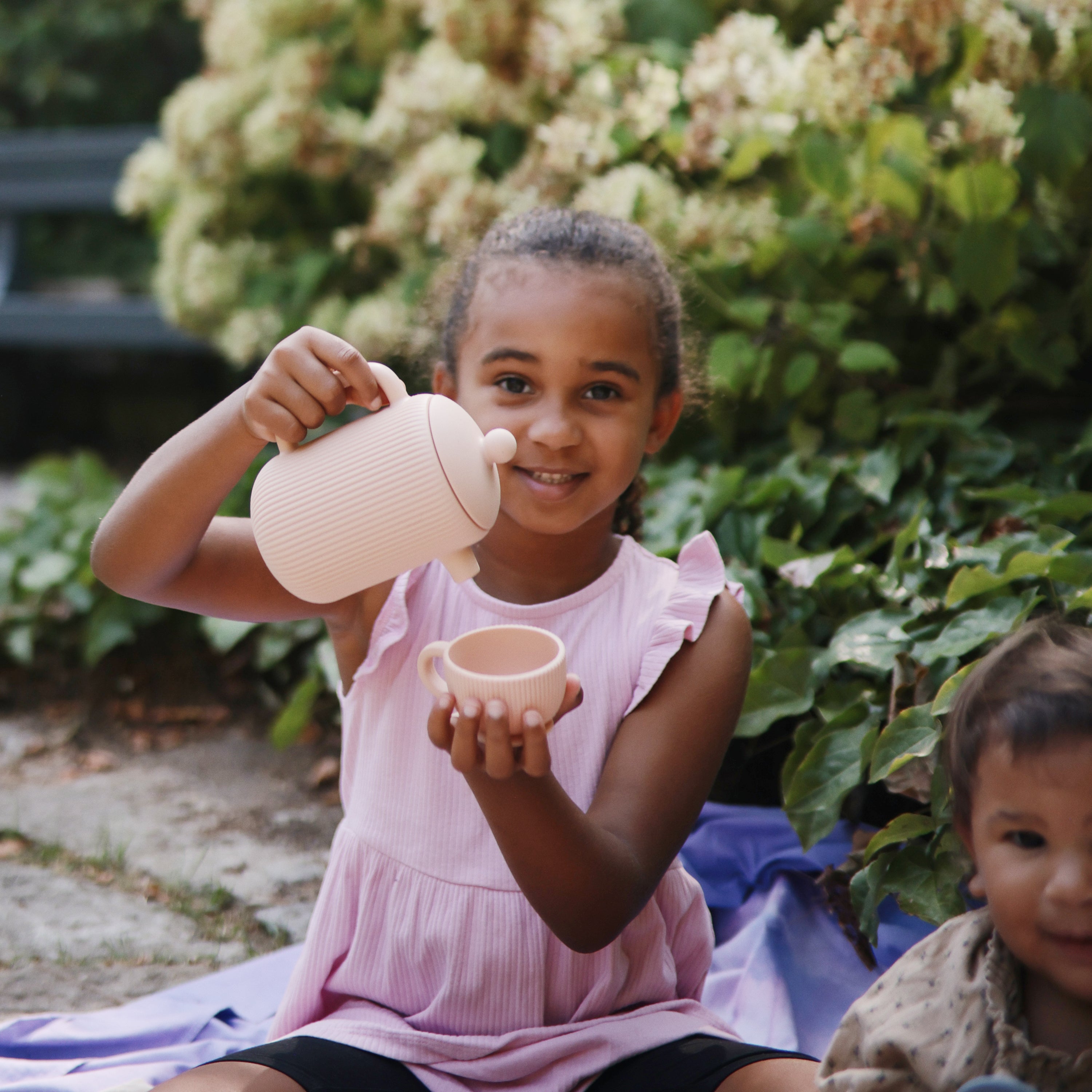 Enfant souriant servant le thé avec la dînette Mushie