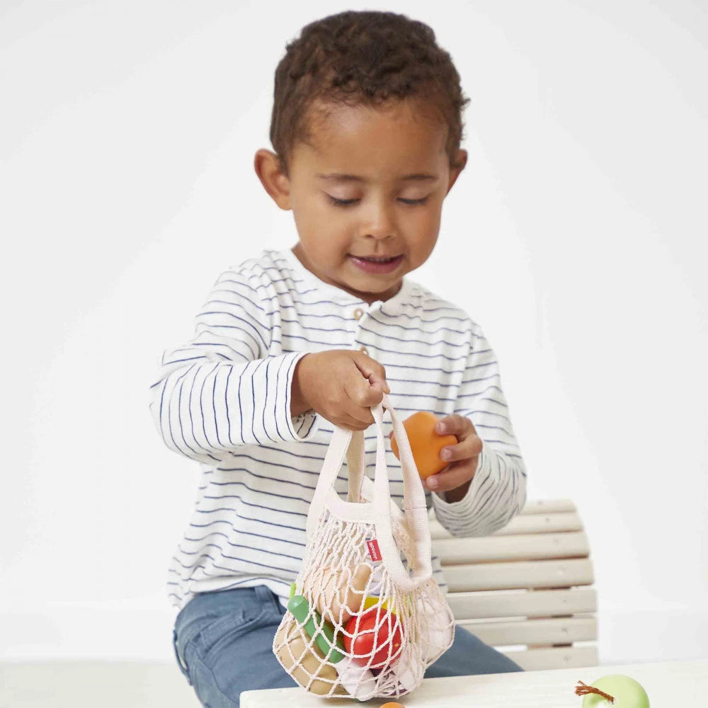 Enfant jouant avec le filet de fruits et légumes Janod