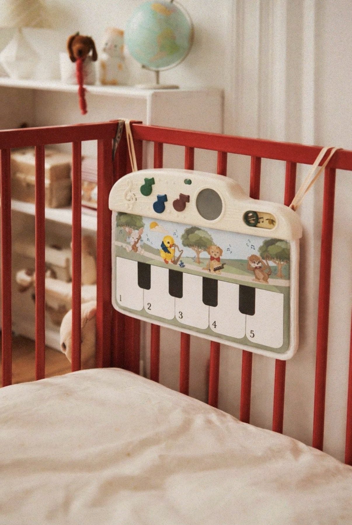 Tapis d'éveil Melody fixé aux barreaux d'un lit à barreaux
